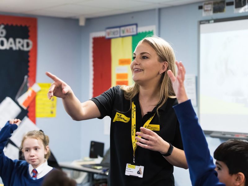 Education officer interacting with school children in a classroom and teaching them about how to interact with dogs in a safe manner.